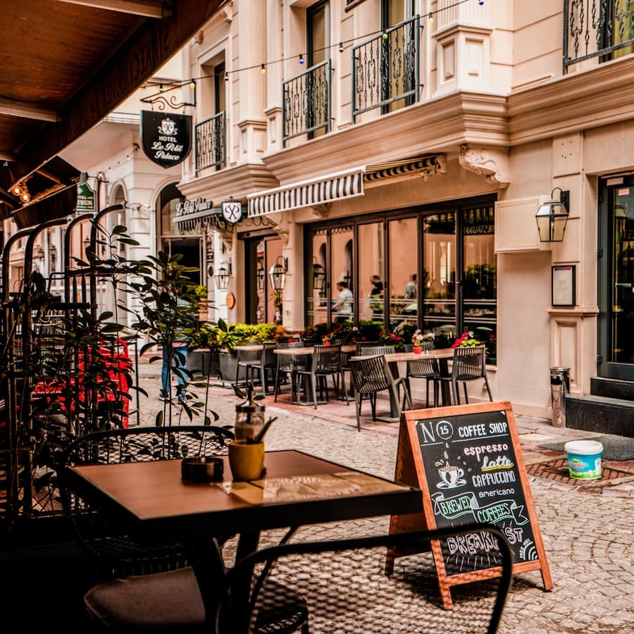 Café tables on a cobbled street beside a chalkboard menu