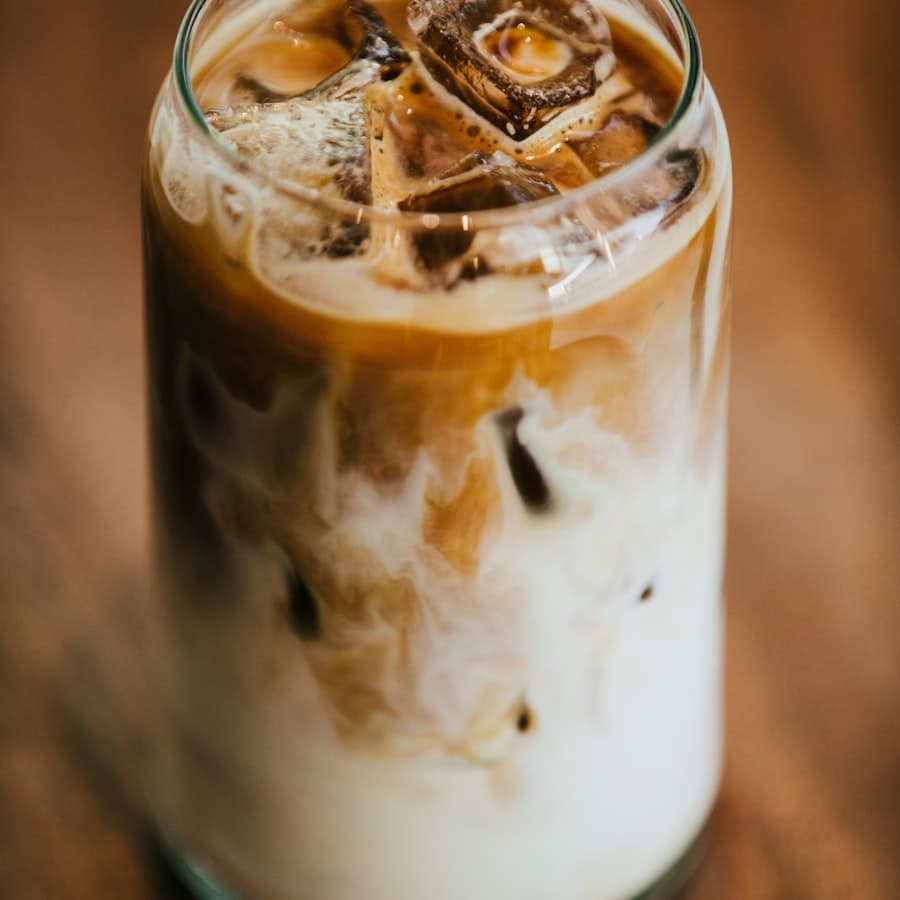 An iced latte in a glass tumbler on a wooden table