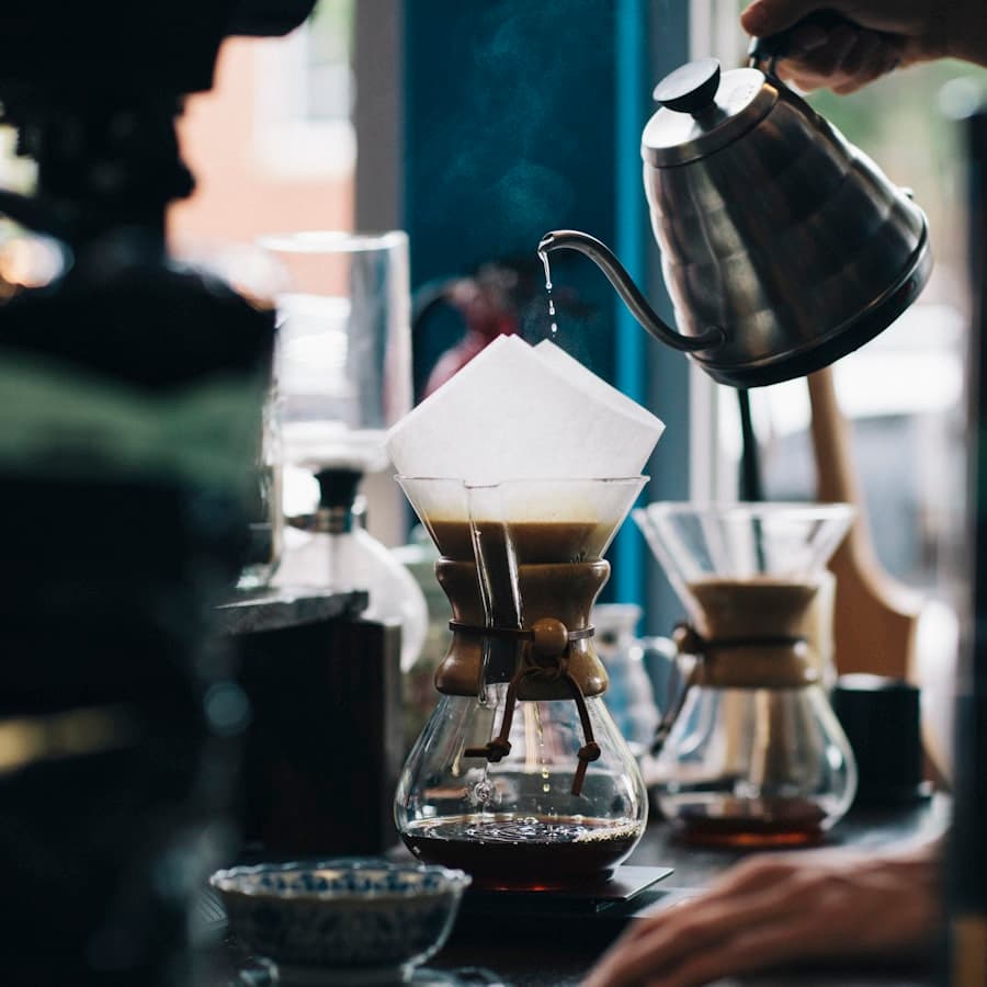 A barista pouring water over a Chemex at the bar