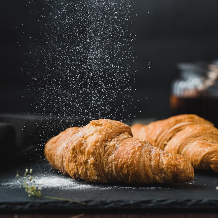 Icing sugar falling over a croissant on a slate board
